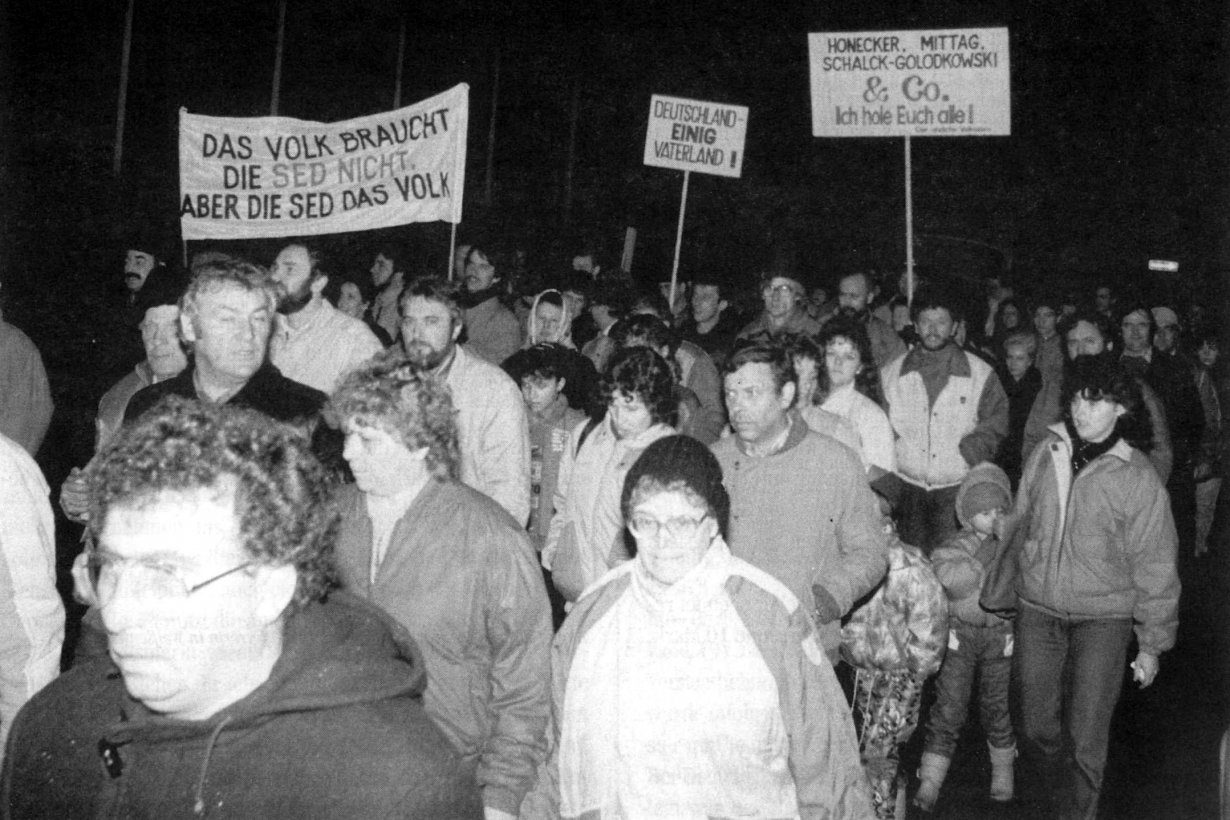 Demonstraten mit Bannern: Das Volk braucht die SED nicht. Aber die SED das Volk; Deutschland Einig Vaterland; Honecker, Mittag, Schalck-Golodkowski & Co. Ich hole euch alle!